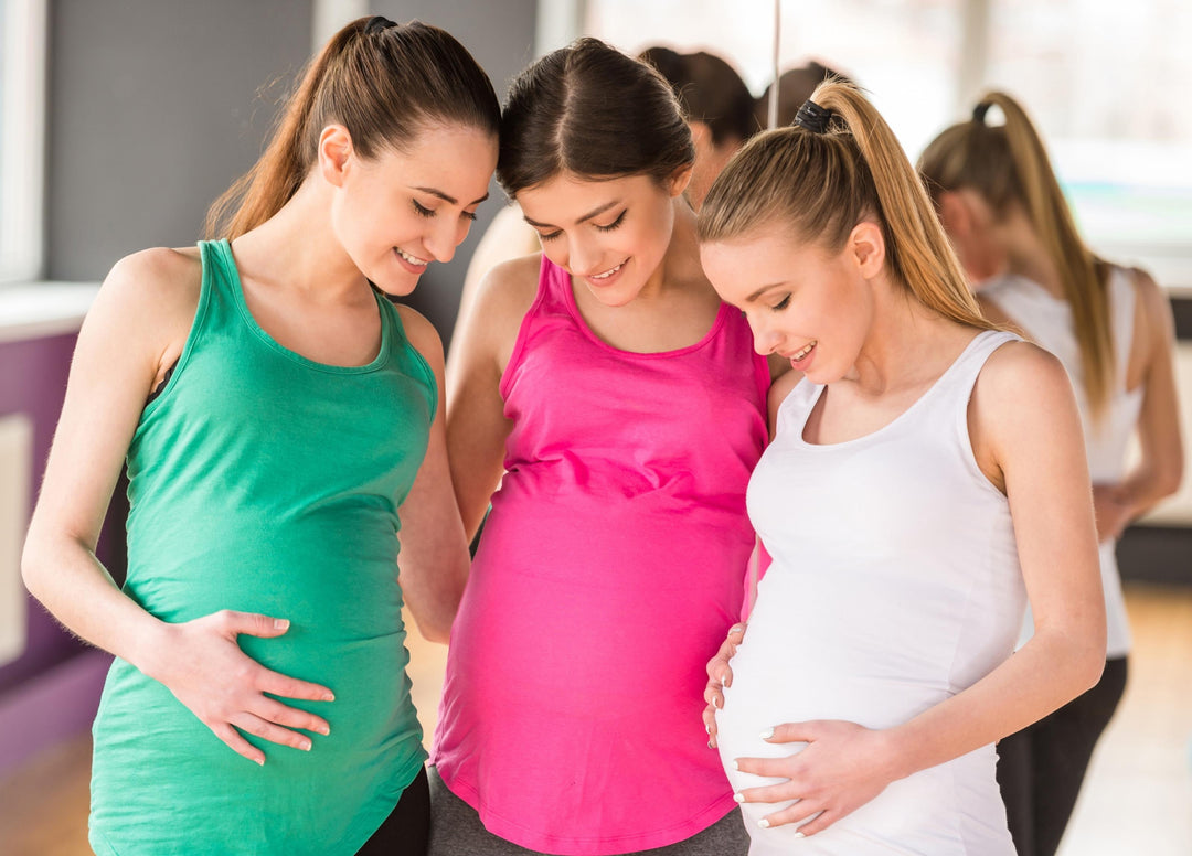 Three pregnant women with strong joints and ligaments, one of the positive benefits of collagen during pregnancy, are at a gym to work out