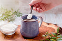 Woman adding collagen wound healing powder to her morning coffee
