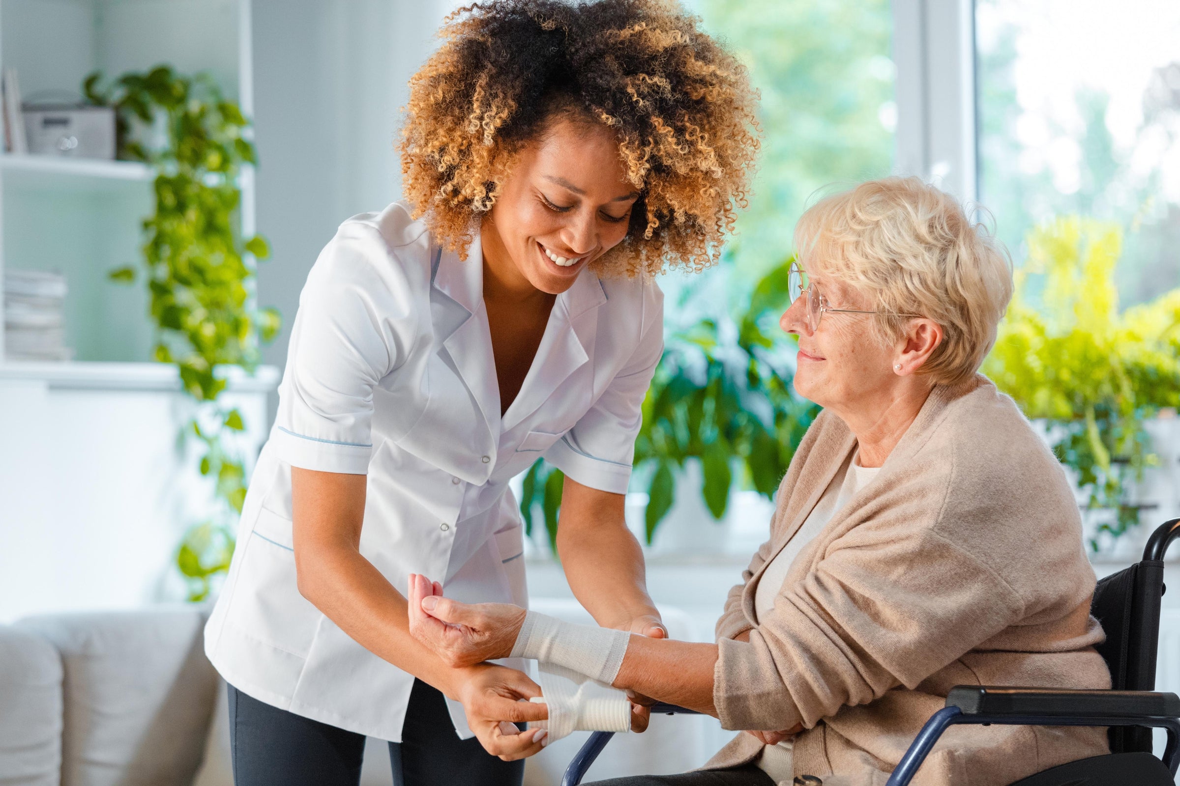 Nurse educating an elderly woman about: “Do wounds heal faster covered or uncovered?” while bandaging the patient’s arm with medical gauze