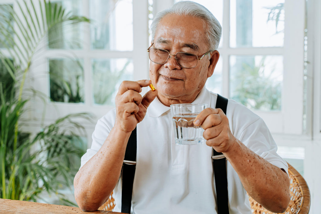 Elderly man holding a glass of water is looking at his medicine, one of the many diabetic wound healing products in the market