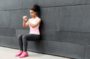 Young woman doing wall sits to shorten recovery time for knee surgery