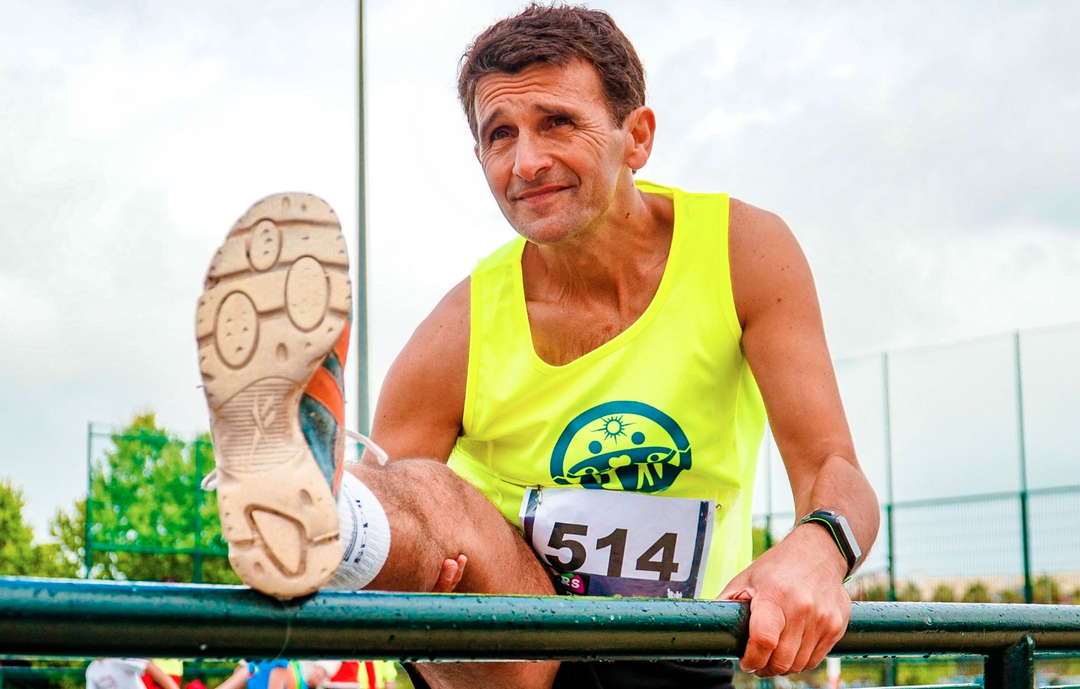 Elderly marathoner who has incorporated food for healthy joints into his athletic diet is stretching his leg before a race