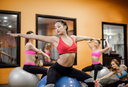 Young flexible woman practicing pilates on a fit ball in a modern studio while thinking, “Does protein help you lose weight?”