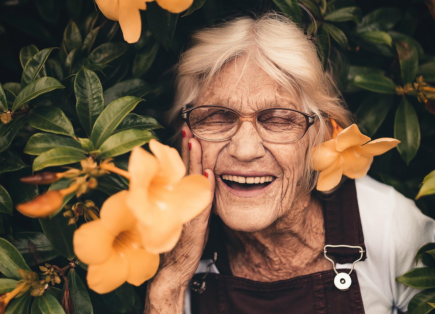 Laughing senior woman against golden trumpet vine is starting to feel pain-free after weeks of taking collagen for arthritis