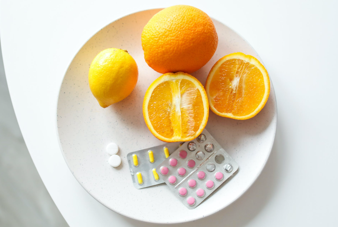 Oranges and vitamins for medical nutrition on a white plate