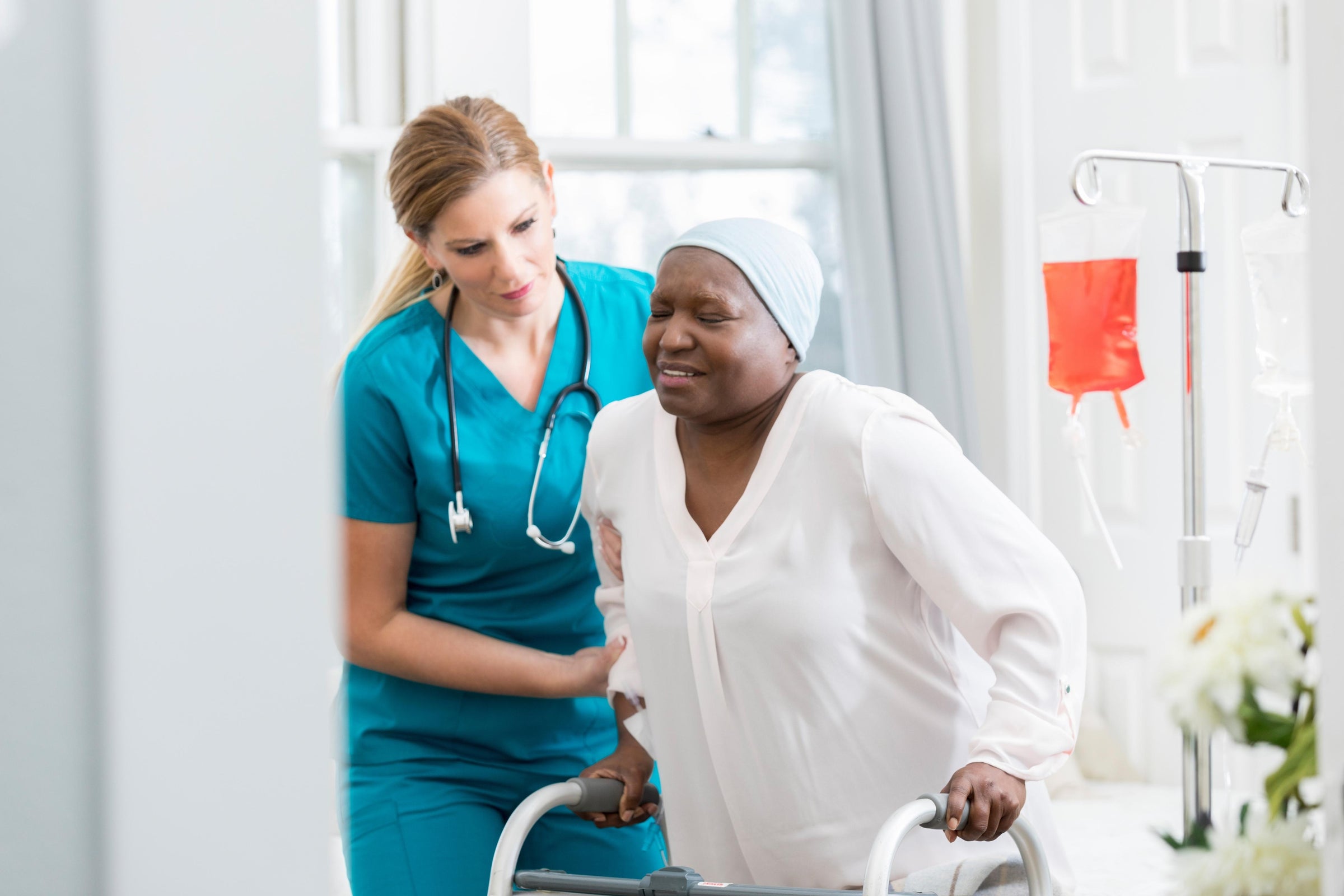 Nurse assisting a patient on a walker while educating her about how a diabetic wound can heal faster