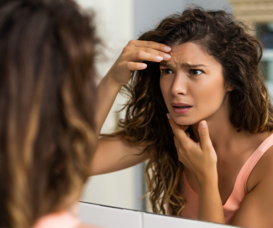Worried woman looking in a mirror while checking the visible signs of collagen deficiency on her face