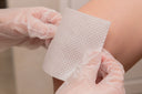 Nurse putting collagen dressing for open wound treatment onto a patient’s knee
