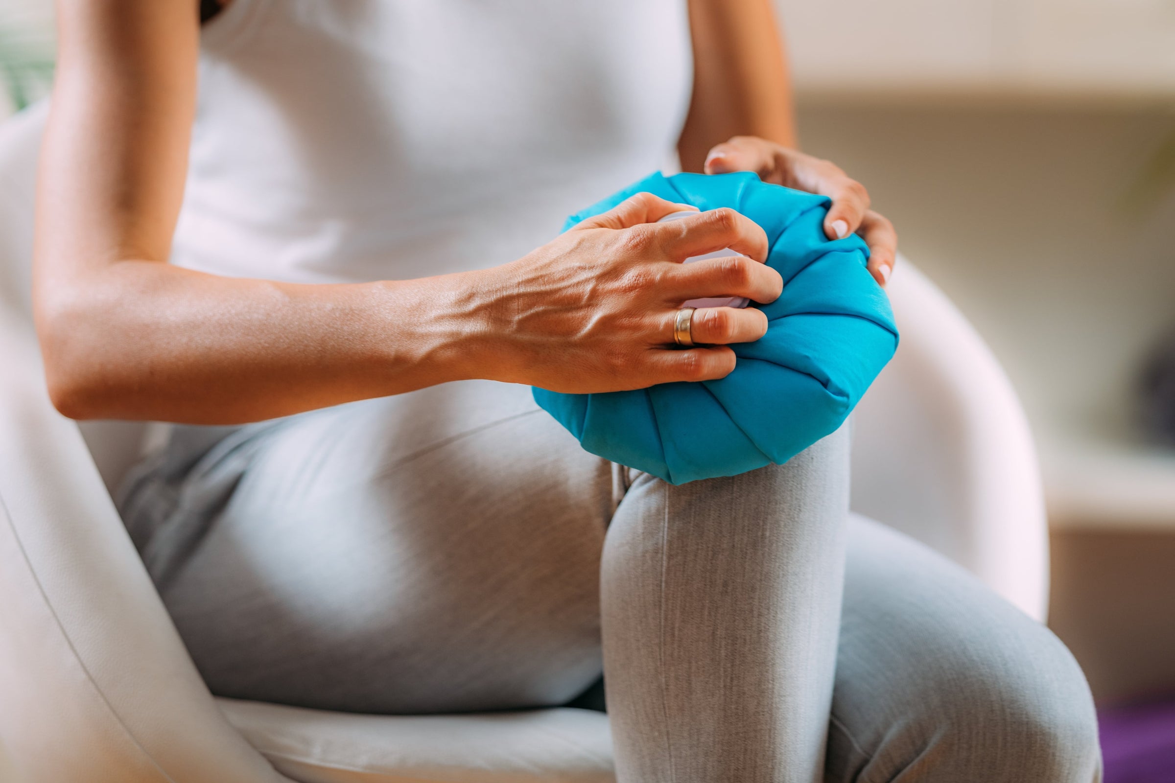 Woman holding a cold compress over her painful knee — one of the home remedies for knee pain