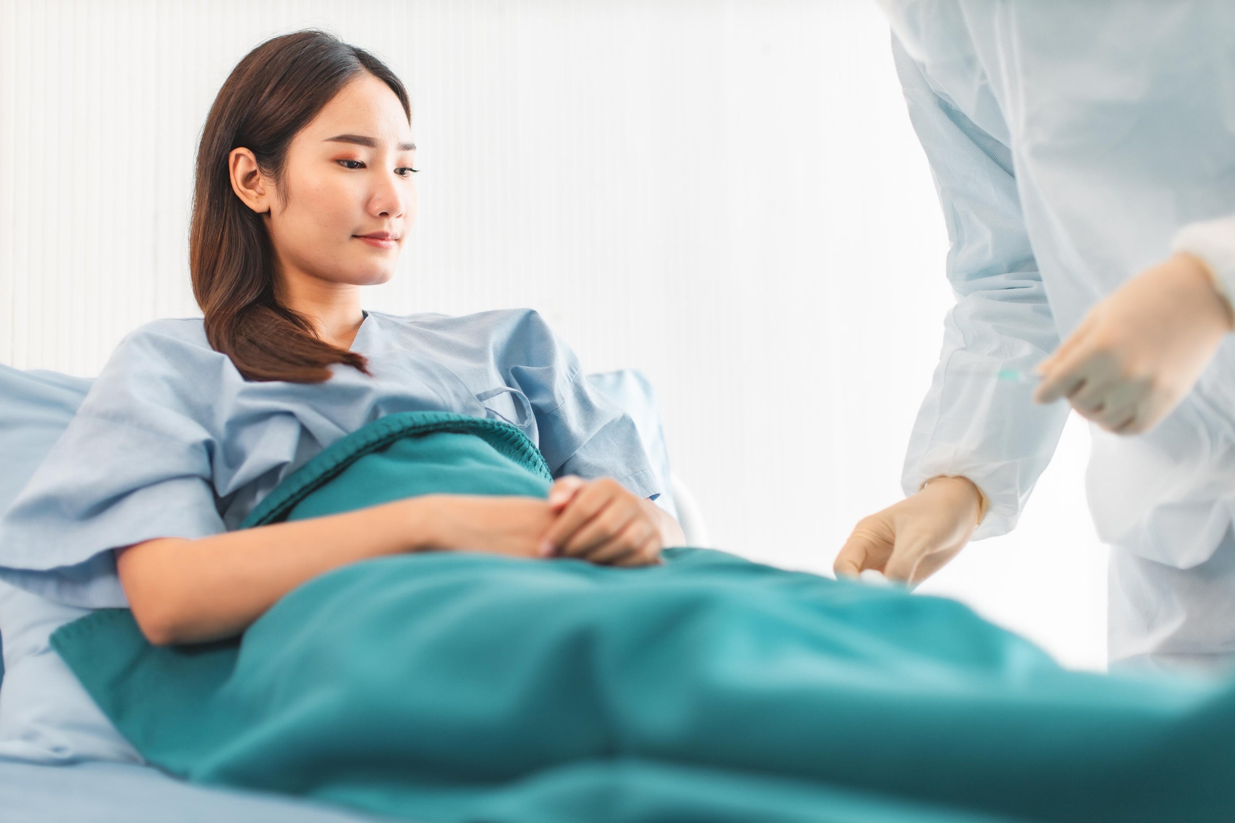 Nurse assisting a patient on hospital bed and educating her on how to prevent bed sores