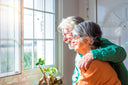 Elderly woman on a pre-bariatric surgery diet looking out the bright window with her loving husband