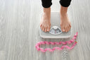 Woman on a weighing scale wondering, "Is collagen good for weight loss?"