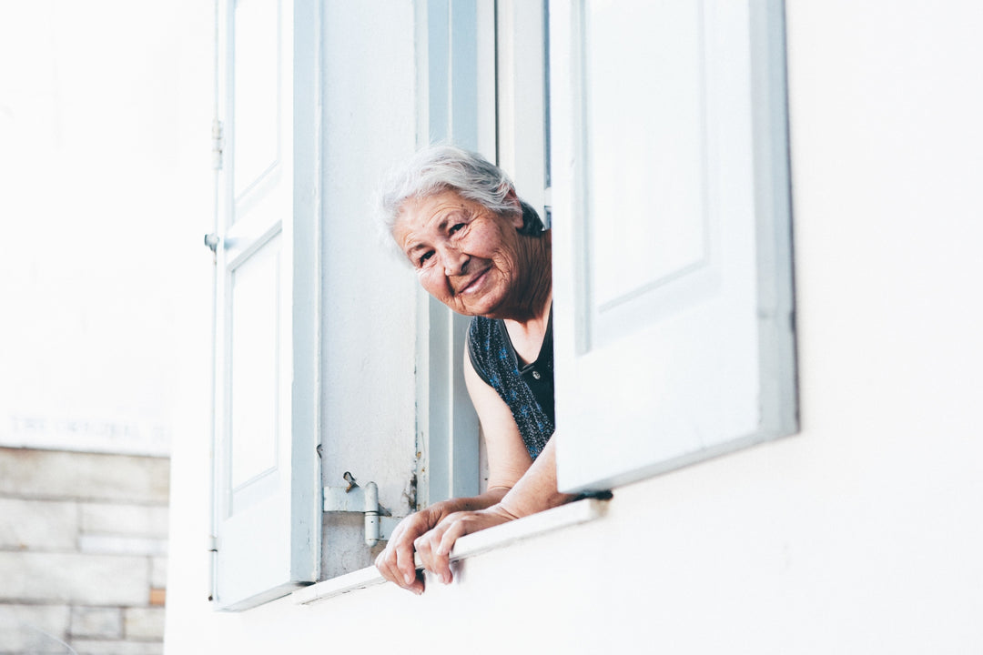 Elderly woman aware of women's hormone health is looking outside her window