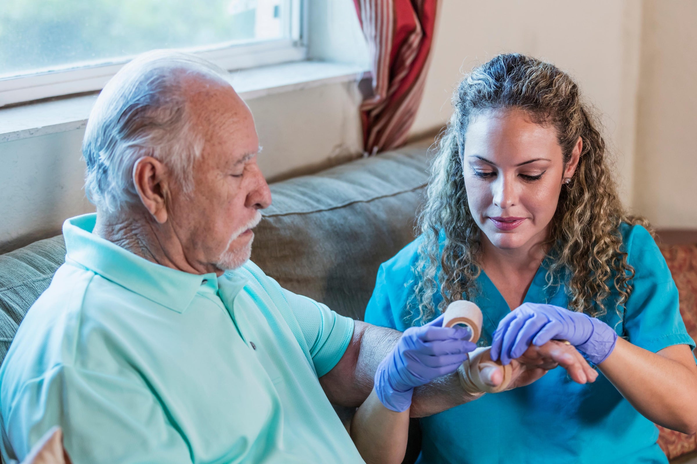 Nurse putting a bandage around an elderly patient's hand going through different stages of healing wound