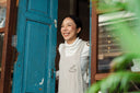 Smiling woman with beautiful skin thanks to the best collagen supplements for women is looking outside her blue wooden double door