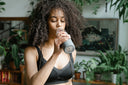 Woman drinks water from her tumbler after taking natural hormone balance supplements