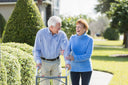 Wife assisting her husband who's using a walker after hip replacement surgery