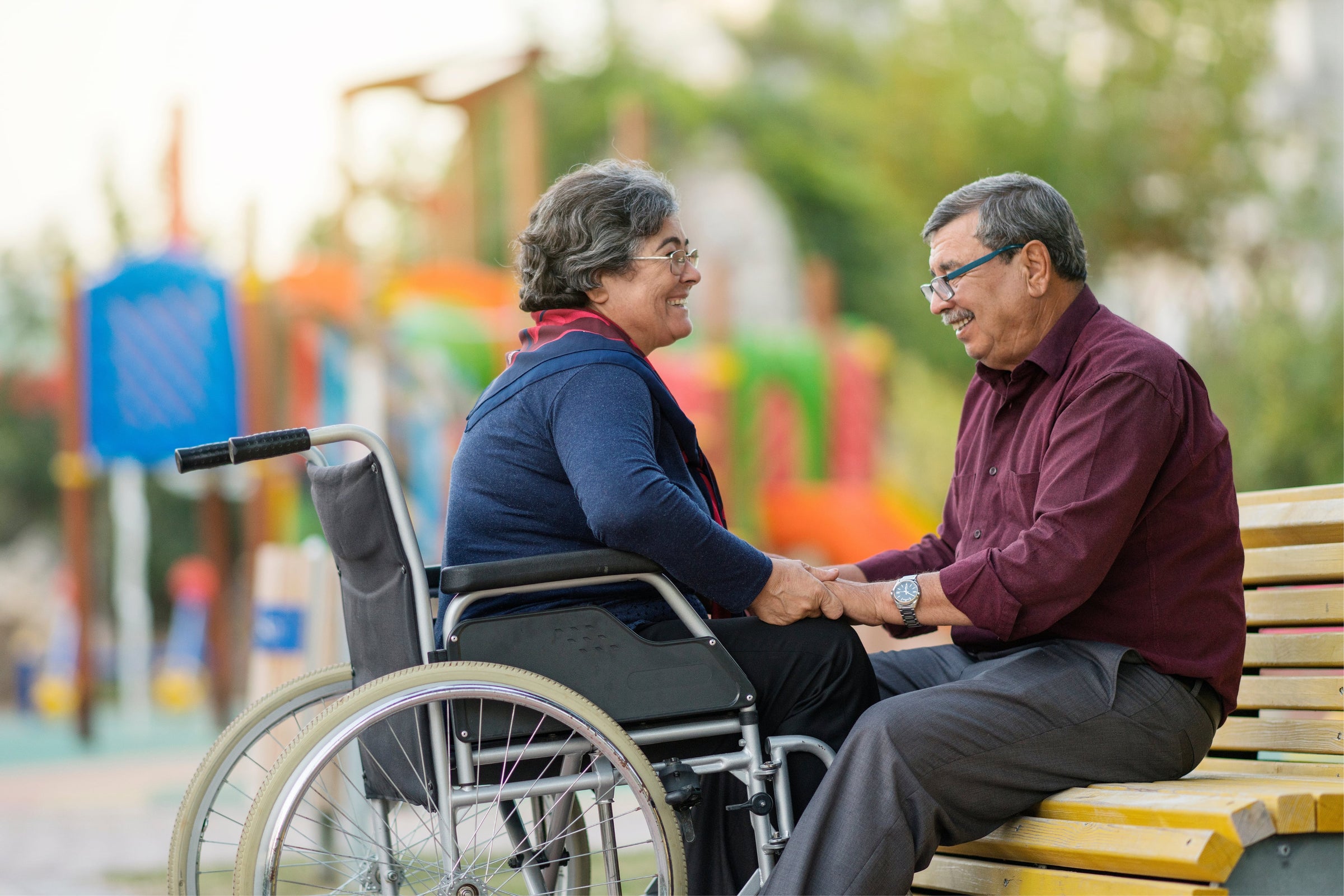 Husband talking to his wife who's on a wheelchair about how long does a wound take to heal while sitting in a park