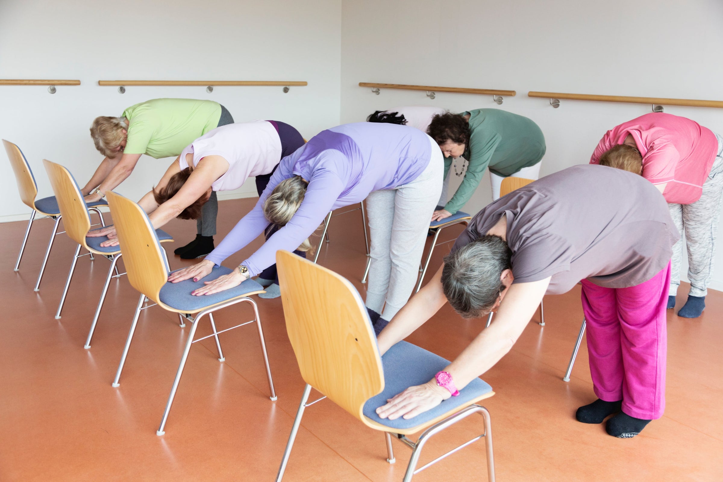 Group of senior women doing arm stretches on chairs — one of the best ways on how to treat frozen shoulder