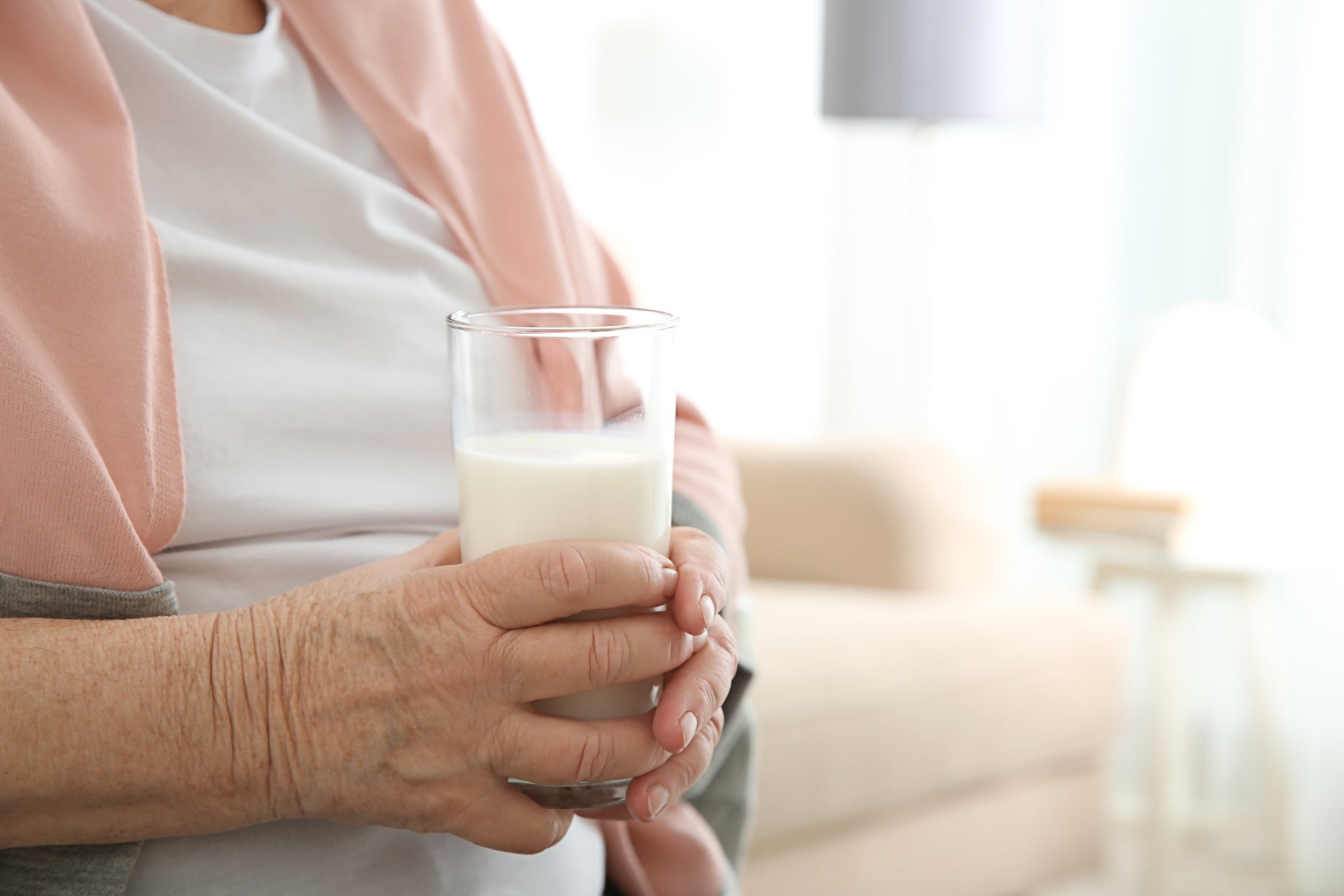 Senior woman holding a glass of nano-hydrolyzed liquid collagen—a knee pain arthritis relief