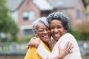 Two happy women who love nutrient-dense snacks hug each other