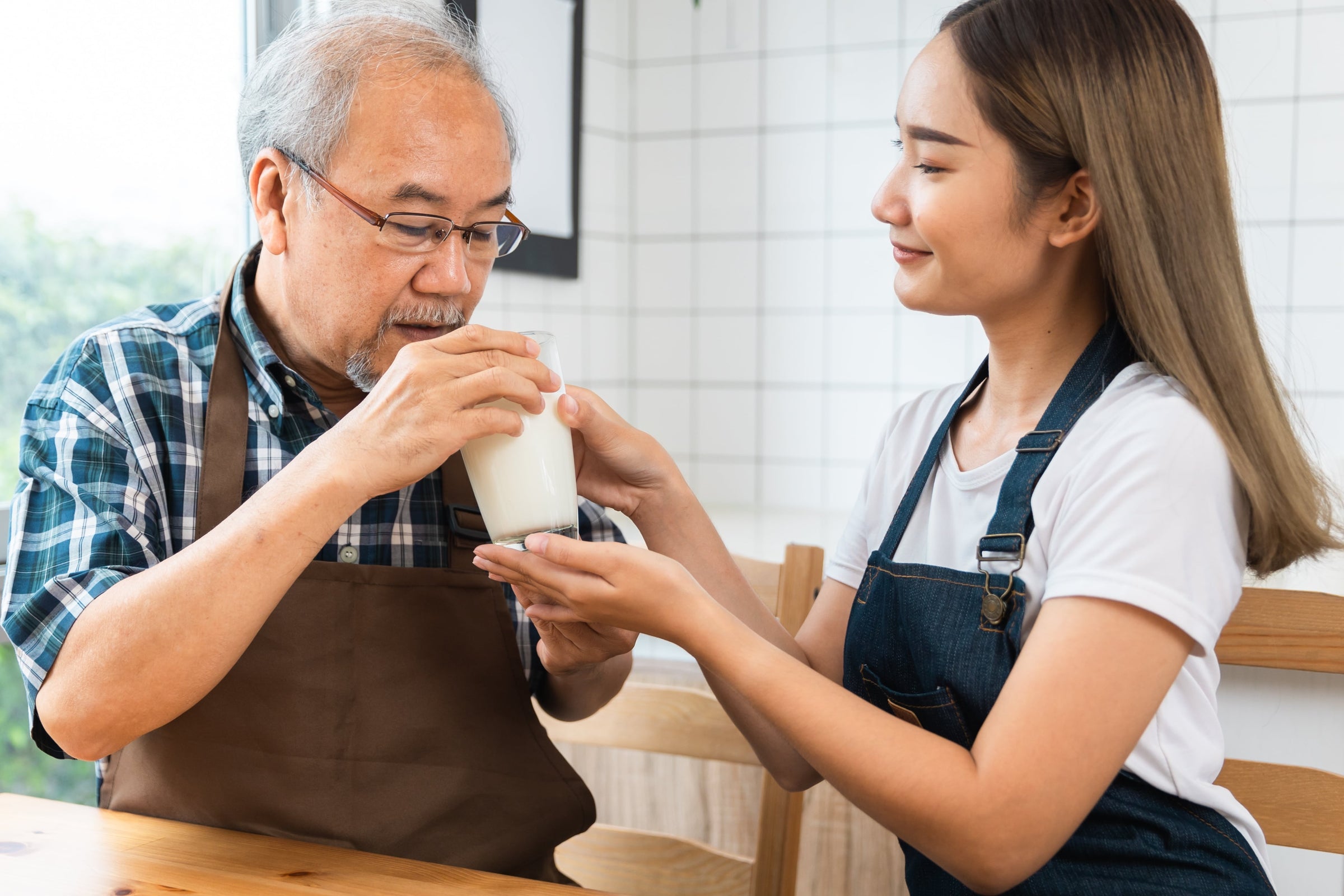 A young Asian daughter prepares a collagen drink for her older parent as part of his rotator cuff tear treatment