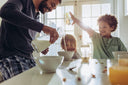 Father pouring collagen peptides - liquid protein onto his kid's bowl