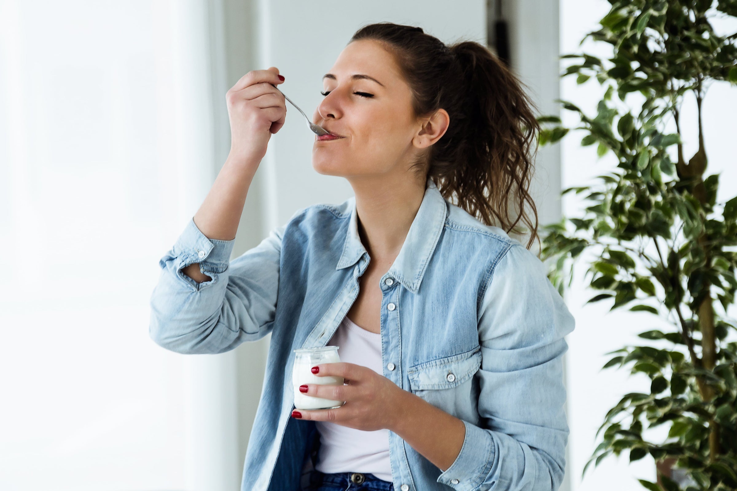 Woman is eating yogurt: one of the best foods to eat when you have no appetite
