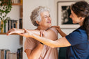 Happy senior woman doing wound care exercise at home with her granddaughter